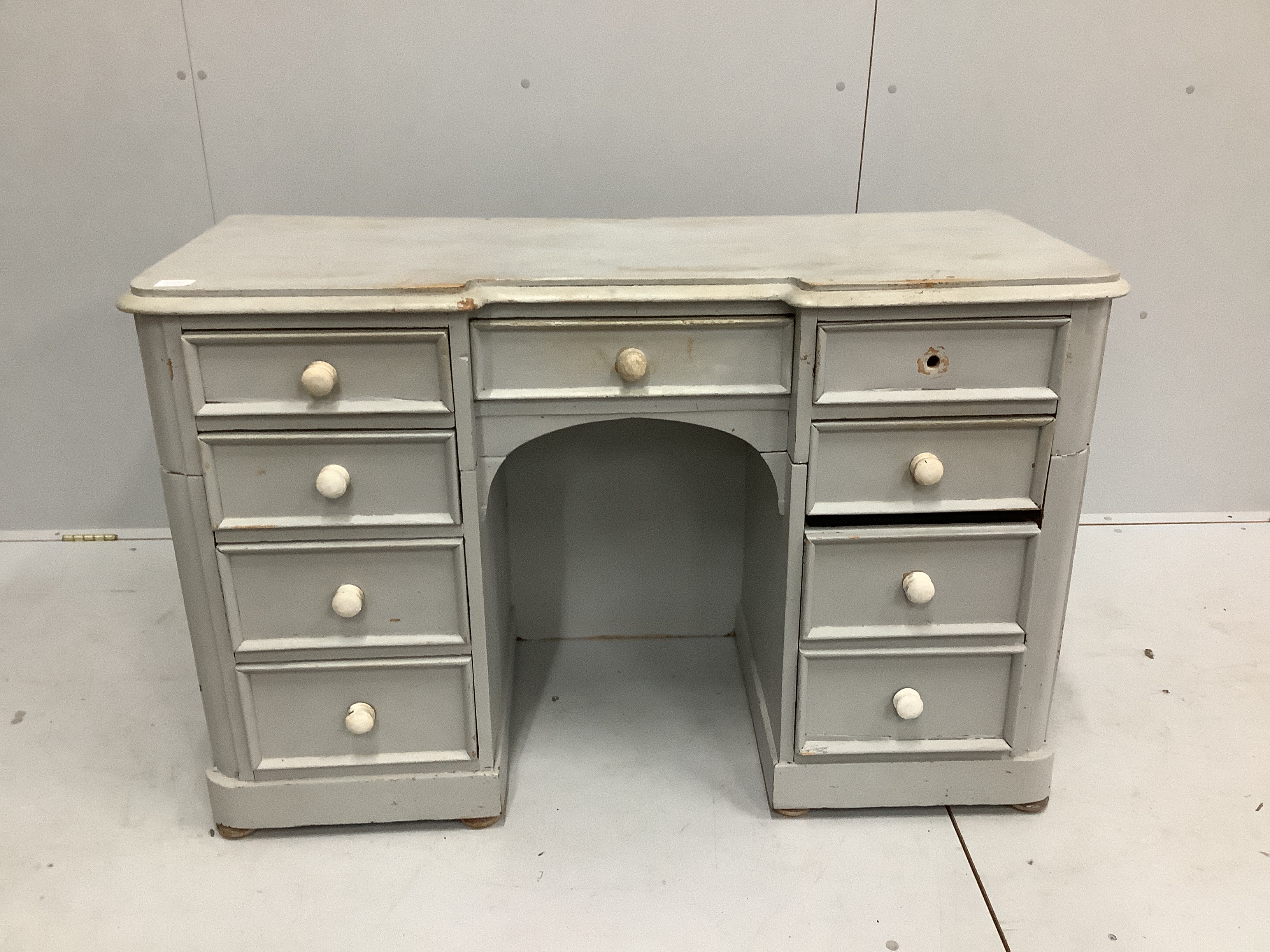 A Victorian pine inverse breakfront kneehole dressing table, cut and later painted, width 122cm, depth 50cm, height 78cm